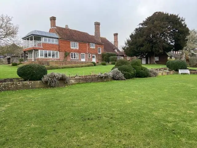 an external image of a redbrick house with three chimneys and a balcony